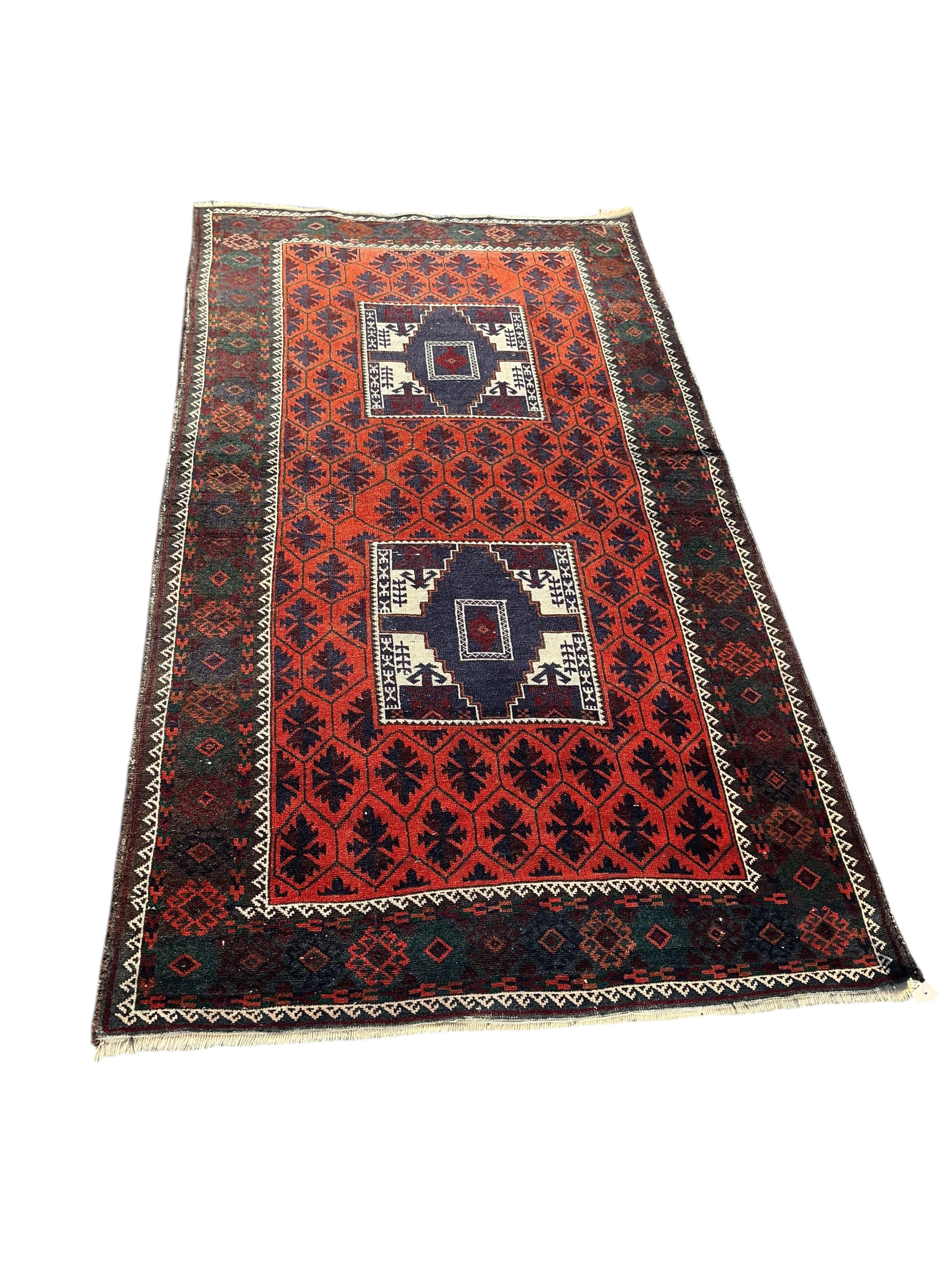 A Belouch twin medallion red ground rug, 194 x 107cm